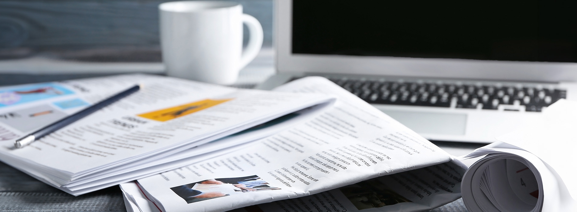 The image shows a cluttered desk with various items, including papers, a laptop, a cup, and a keyboard, suggesting a busy work environment.
