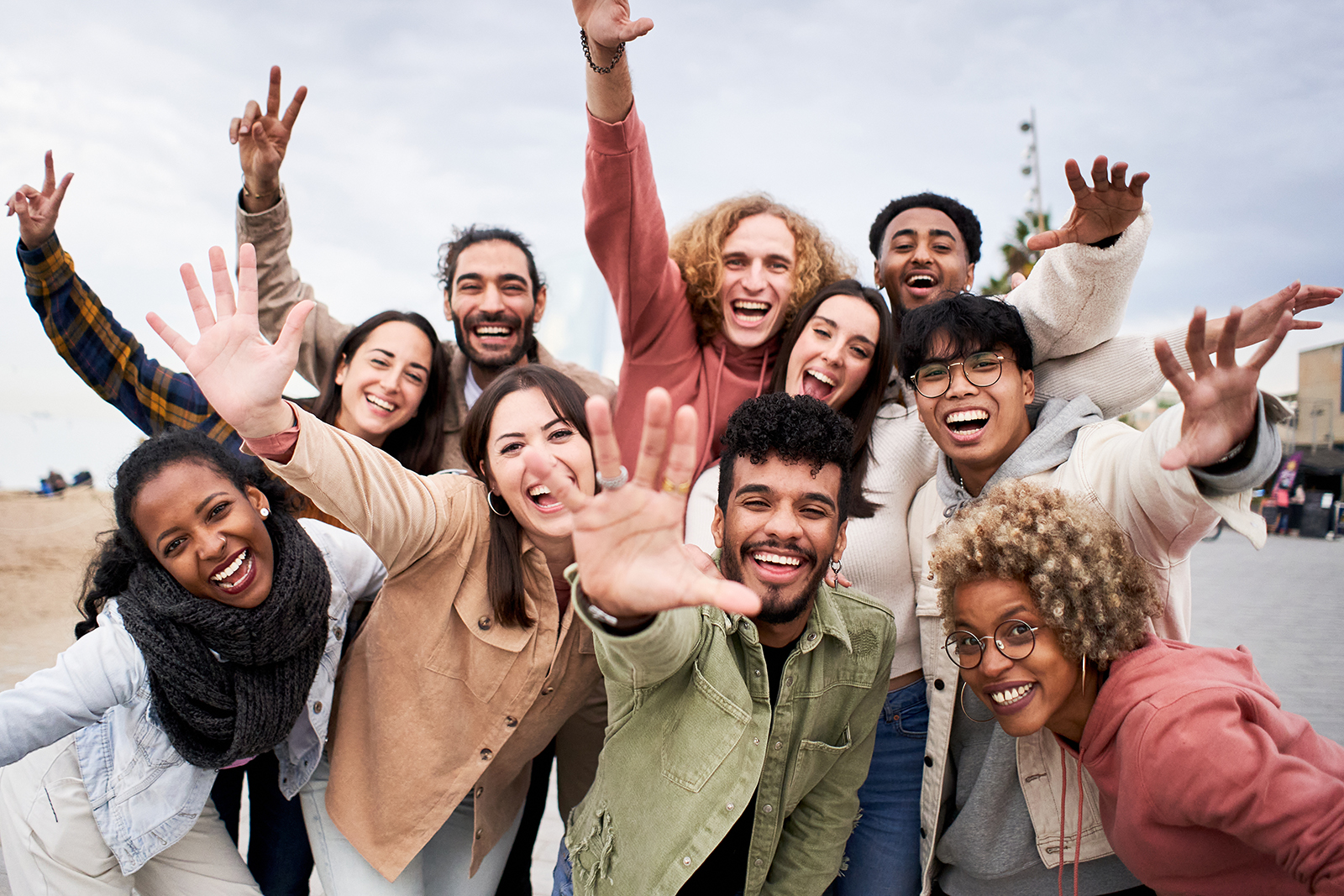 A group of people celebrating with raised arms and open smiles, standing together outdoors.