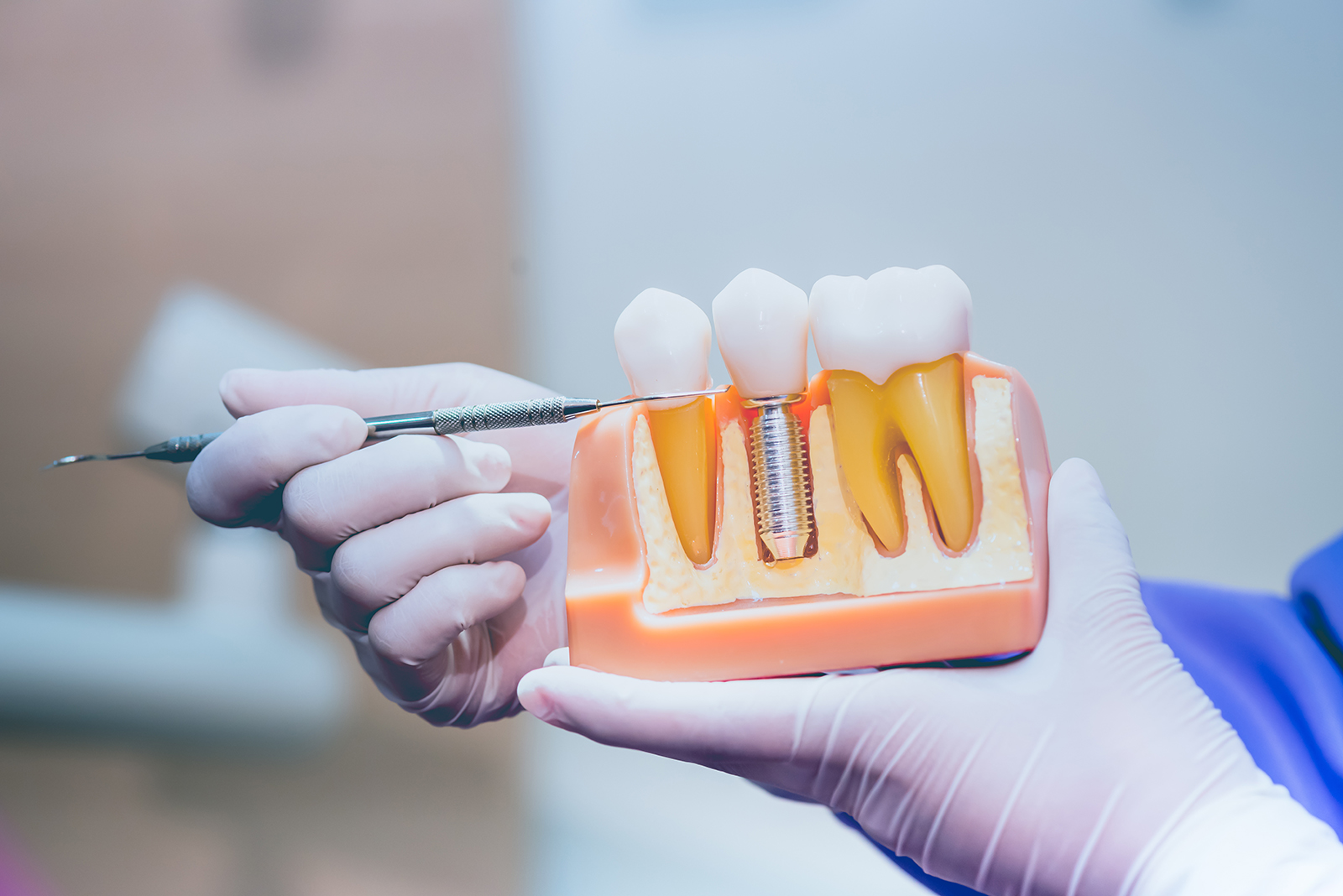 A person is holding a tray with two rows of teeth, each row containing a single tooth, and they are using a tool to manipulate one of the teeth.
